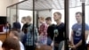 Seven men who received sentences of six to 18 years appear in court in the Volga Military District Court in Russia. 