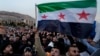Syrian citizens wave the revolutionary flag and shout slogans as they celebrate in Damascus on December 9.