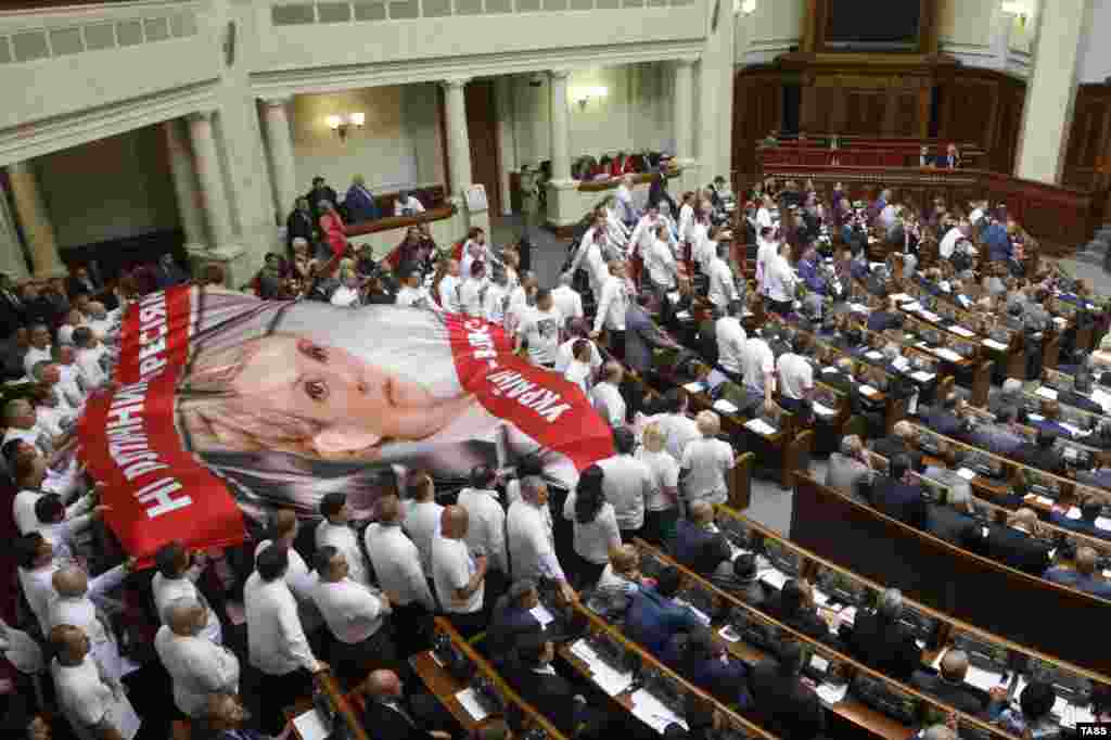 Жогорку Раданын оппозициячыл депутаттары Тимошенкого колдоо иретинде парламентте анын плакатын жайып жатышат. 2013-жылдын май айы.&nbsp;
