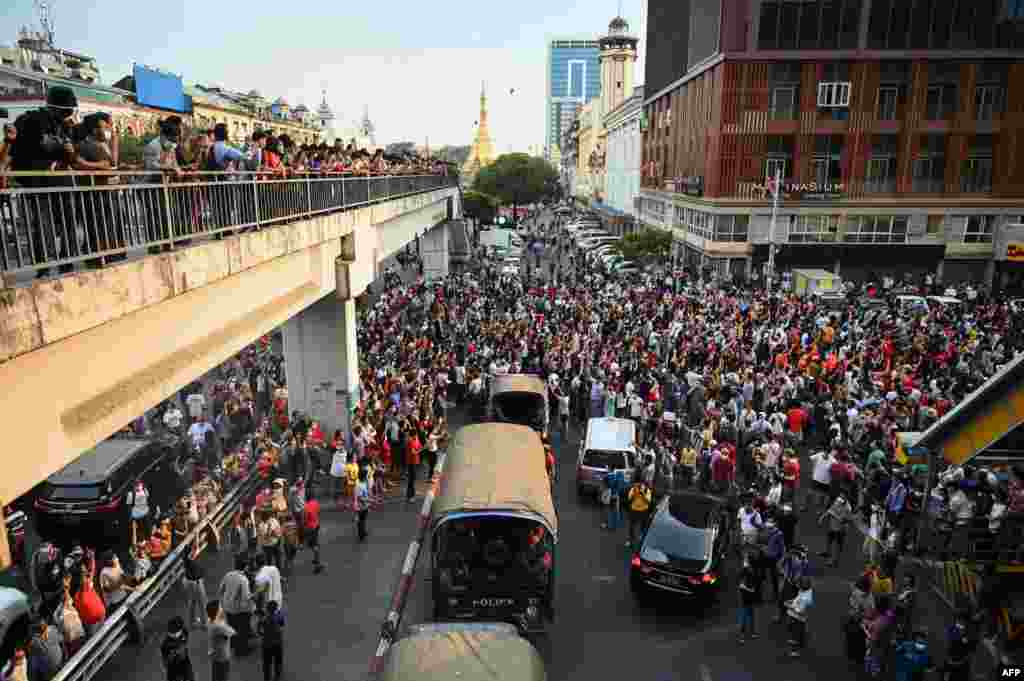 Mașinile de poliție își fac loc printre manifestanți (Photo by YE AUNG THU / AFP)