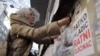 Aida Ćorović lepi plakate sa natpisom "Ratko Mladić ratni zločinac" na protestu u centru Beograda, novembar 2021. godine.