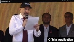 Armenian Prime Minister Nikol Pashinian reads out a draft referendum manifesto during a campaign rally in Goris, March 11, 2020