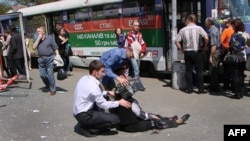 Two men try to help a woman injured by one of the blasts in the eastern Ukrainian city of Dnipropetrovsk on April 27. 
