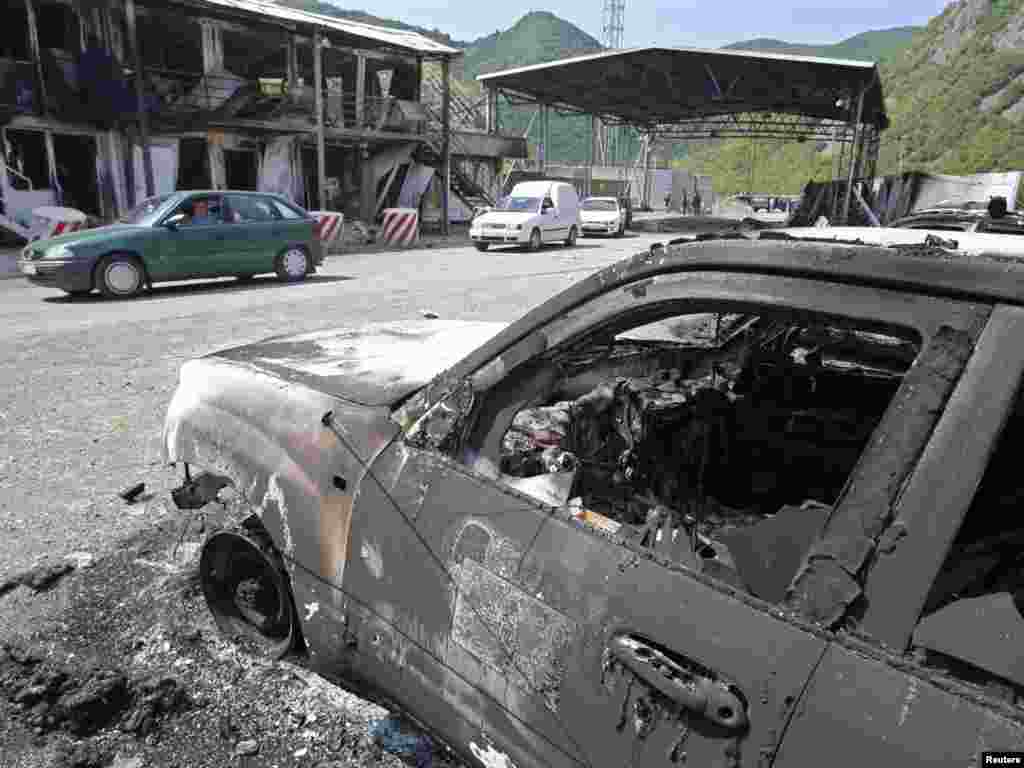 Vozila prolaze pored zapaljenih automobila na granici Kosova i Srbije u Jarinju, 28. jul 2011.