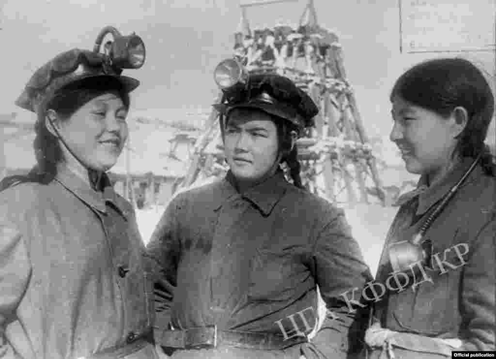 Көк-Жаңгак көмүр кесиминин комсомол-жаштарынын аялдар бригадасынын алдыңкы эмгекчилери. Таш көмүрдү уратып түшүрүүчү жана конвейерге жүктөп туруучу жумушчу П. Атибаева, ат айдагычтар П. Карабаева жана А.Калиева жумуш башталар алдында. Көк-Жаңгак шаары. 1943-жыл. 