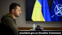 Президентът на Украйна Володимир Зеленски на фона на знамената на Украйна и НАТО. Снимката е от ноември 2022 г.