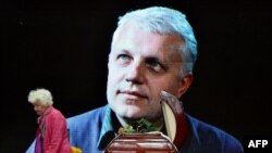 A woman pays tribute near the casket and portrait of Belarus-born journalist Pavel Sheremet, who was killed in a car bomb in central Kyiv in 2016. (file photo)