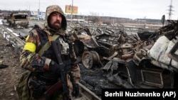 Оборонець України біля знищеної російської військової техніки у Бучі, що неподалік Києва. 1 березня 2022 року